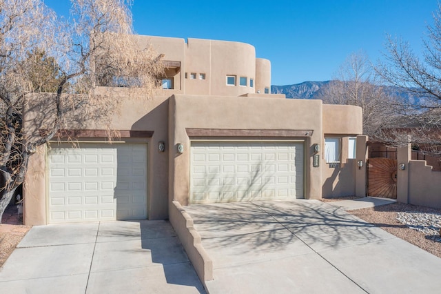 pueblo-style home with a garage and a mountain view