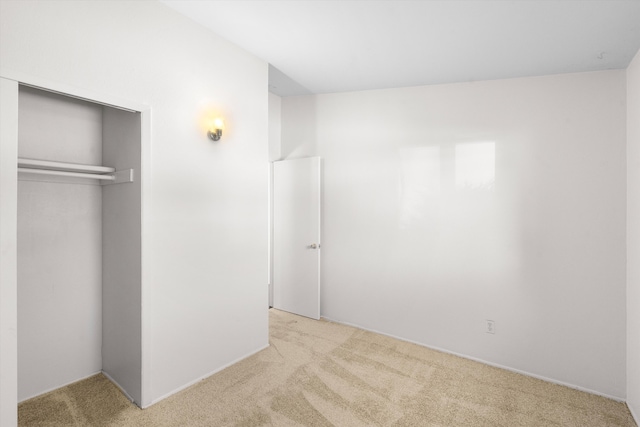 unfurnished bedroom featuring light colored carpet and a closet