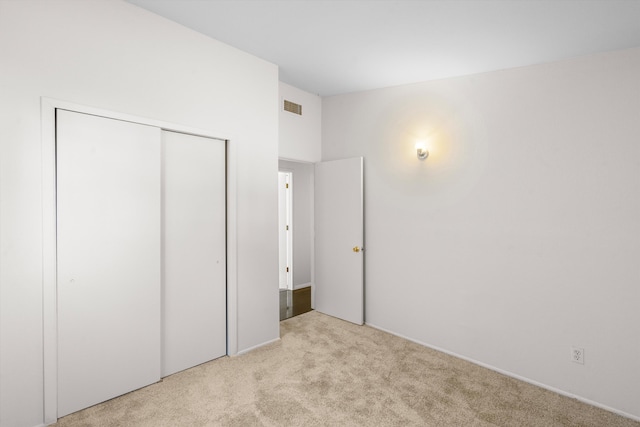 unfurnished bedroom with a closet and light carpet