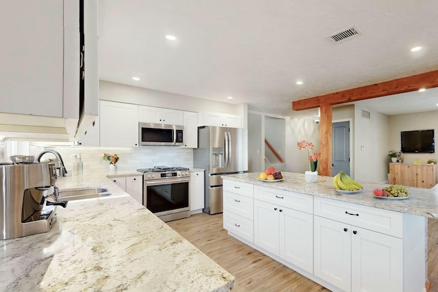 kitchen featuring visible vents, backsplash, appliances with stainless steel finishes, light wood-style floors, and a sink