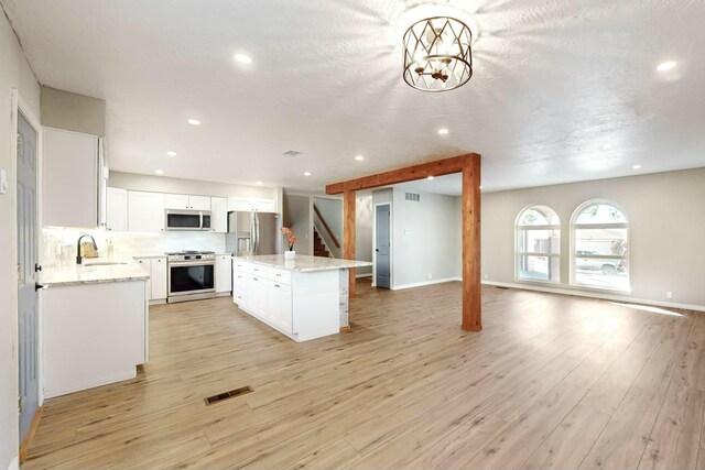 kitchen featuring white cabinetry, sink, a kitchen island, backsplash, and stainless steel appliances