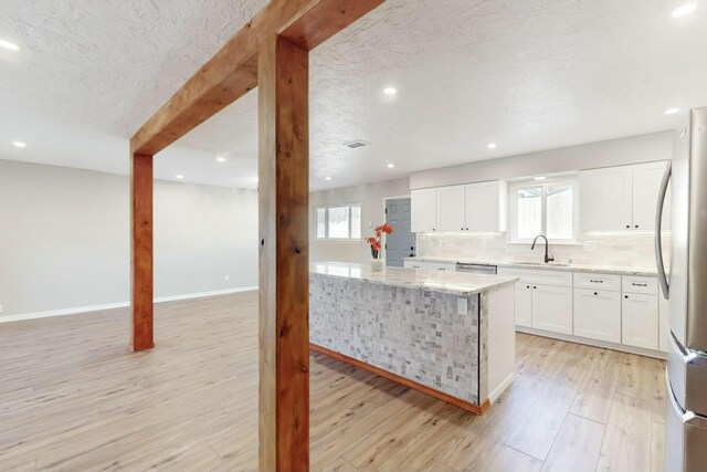 kitchen with light stone countertops, white cabinets, appliances with stainless steel finishes, tasteful backsplash, and light wood-type flooring