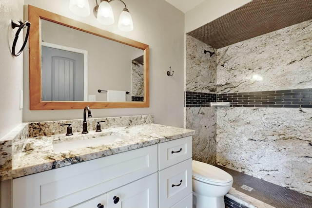 bathroom featuring toilet, vanity, and a tile shower