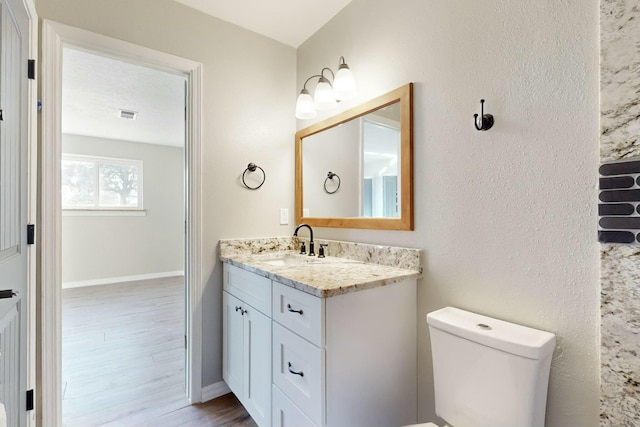 bathroom featuring a textured ceiling, wood-type flooring, toilet, and vanity