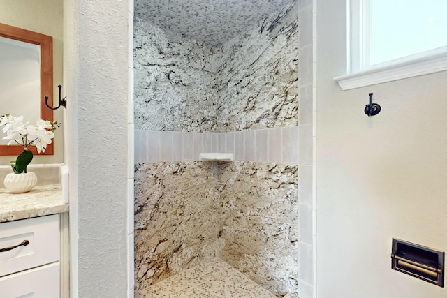 bathroom featuring a tile shower and vanity