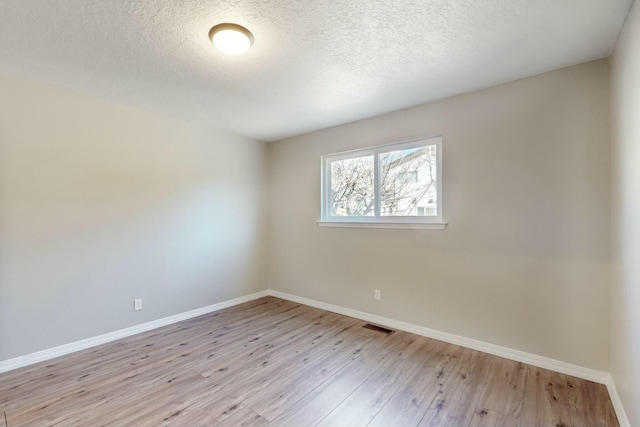 spare room with light hardwood / wood-style flooring and a textured ceiling