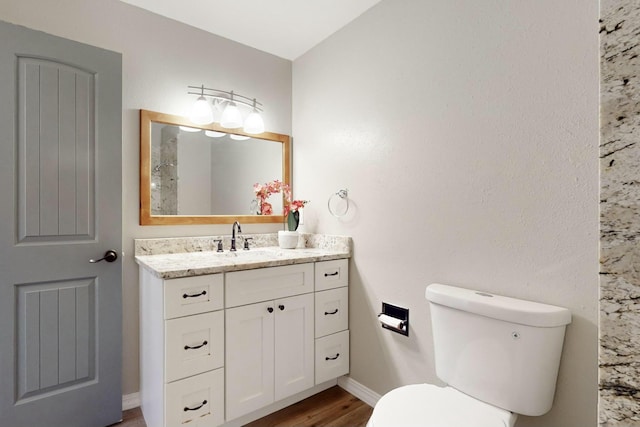 bathroom with hardwood / wood-style flooring, toilet, and vanity