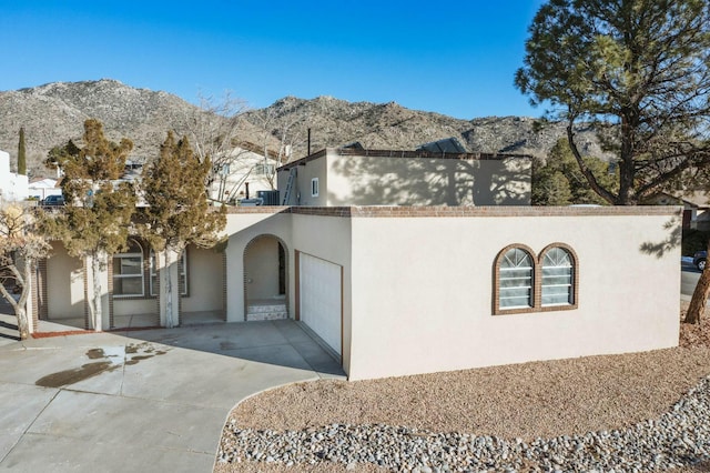 view of front facade with a garage, a mountain view, and central AC