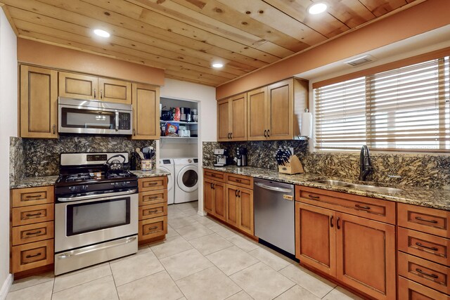 kitchen with sink, washer and clothes dryer, stainless steel appliances, decorative backsplash, and wooden ceiling