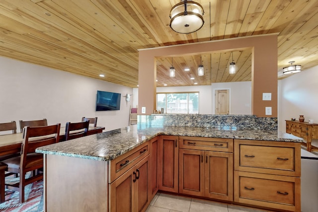 kitchen featuring dark stone countertops, light tile patterned floors, and kitchen peninsula