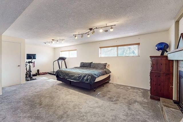 carpeted bedroom with a tile fireplace and a textured ceiling