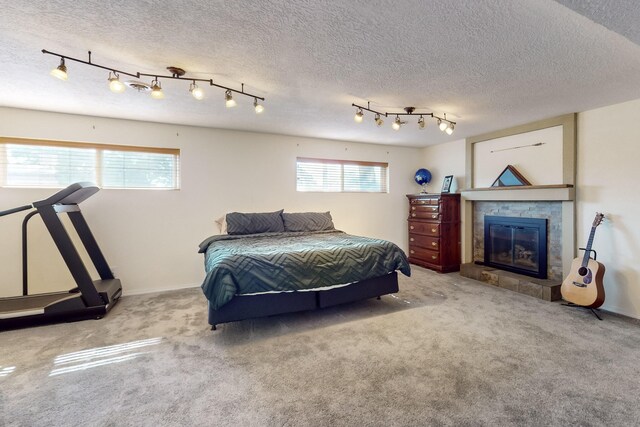 carpeted bedroom featuring multiple windows, a fireplace, and a textured ceiling