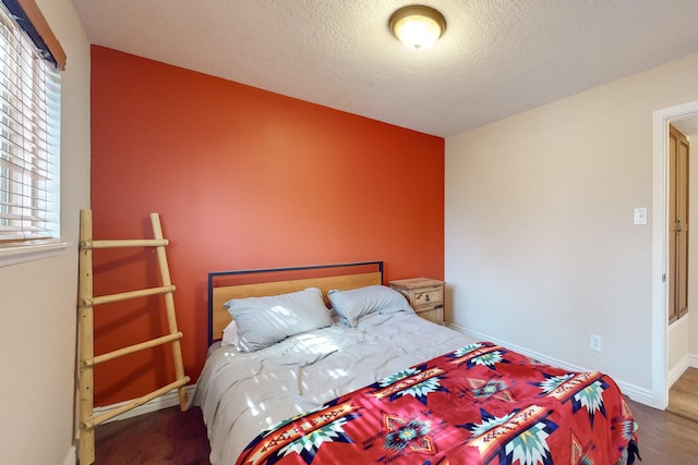 bedroom with hardwood / wood-style flooring, a textured ceiling, and multiple windows