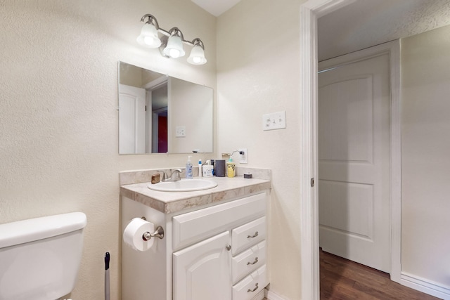 bathroom with vanity, toilet, and hardwood / wood-style floors