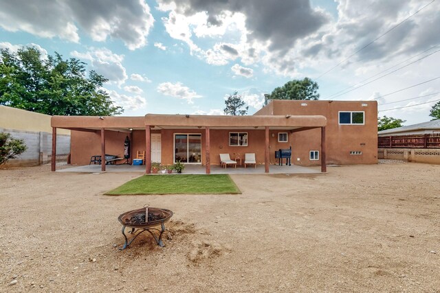 rear view of house with a fire pit and a patio