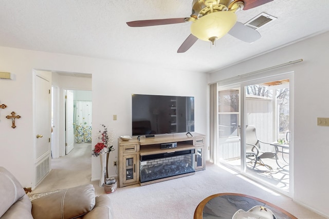 carpeted living room with a textured ceiling and ceiling fan