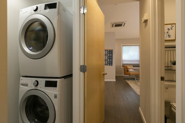 laundry room featuring stacked washer / drying machine and dark hardwood / wood-style floors