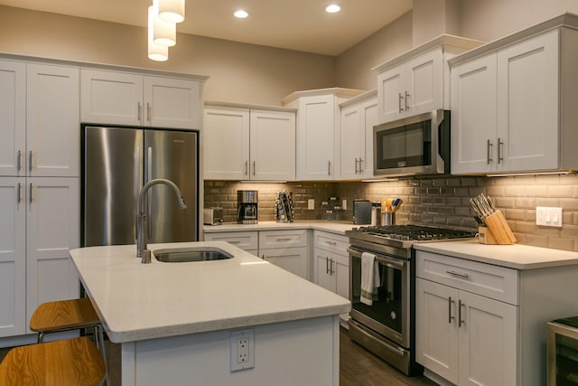 kitchen with tasteful backsplash, stainless steel appliances, a center island with sink, and white cabinets