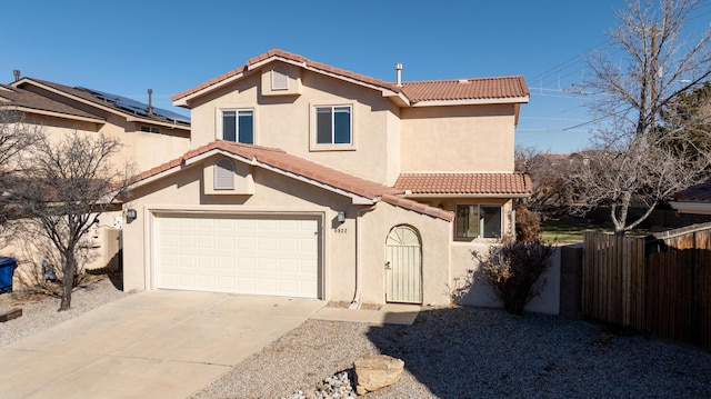 mediterranean / spanish-style home featuring a tile roof, fence, concrete driveway, and stucco siding