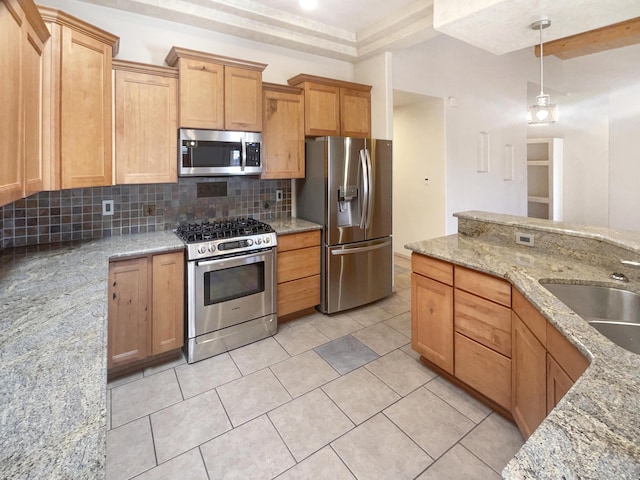 kitchen featuring pendant lighting, decorative backsplash, light stone countertops, and appliances with stainless steel finishes