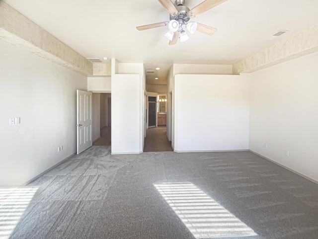 empty room with ceiling fan and dark colored carpet