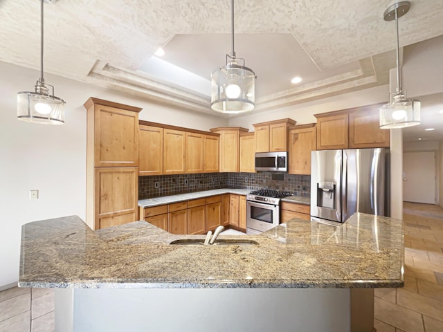 kitchen with a raised ceiling, appliances with stainless steel finishes, and decorative light fixtures