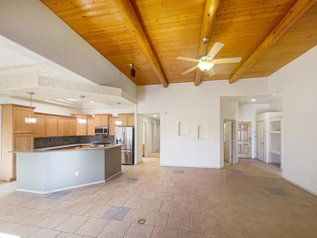 kitchen featuring ceiling fan, appliances with stainless steel finishes, hanging light fixtures, a center island, and tasteful backsplash