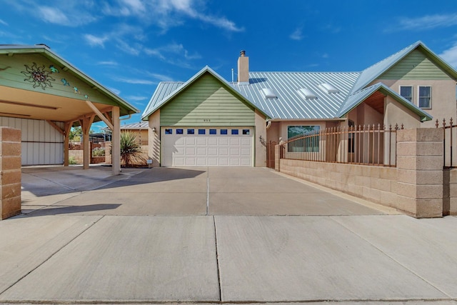 view of front of property with fence, driveway, a chimney, a garage, and metal roof