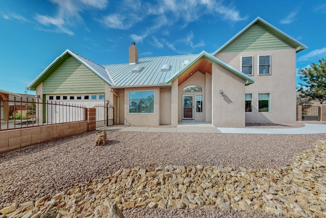 rear view of property featuring a gate, fence, a chimney, and metal roof