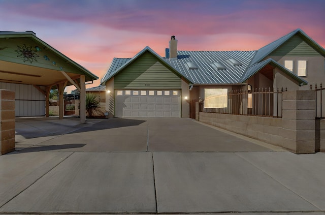 view of front of home featuring an attached garage, fence, driveway, and metal roof