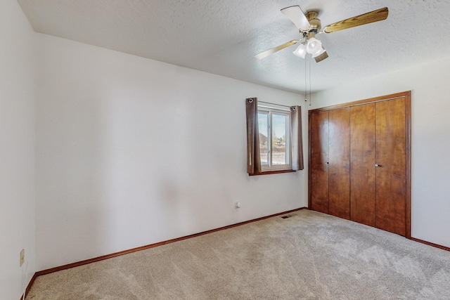 unfurnished bedroom featuring ceiling fan, light carpet, a textured ceiling, and a closet