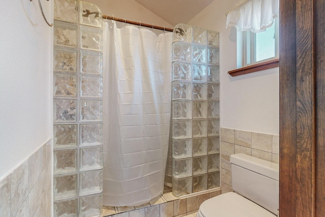 bathroom featuring tile walls, toilet, and tiled shower