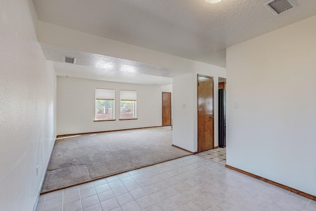 empty room featuring light colored carpet and a textured ceiling