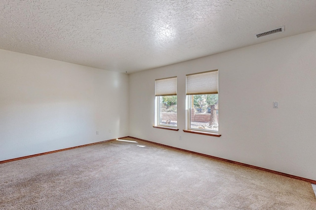 carpeted empty room with a textured ceiling