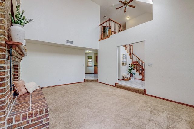 unfurnished living room featuring a towering ceiling, ceiling fan, and carpet flooring