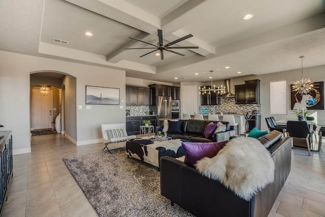 living room with light tile patterned floors, ceiling fan with notable chandelier, and beamed ceiling