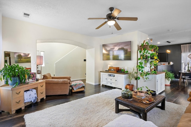 living room with ceiling fan, dark hardwood / wood-style flooring, and a textured ceiling