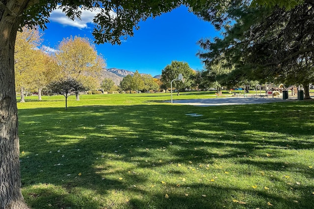 view of property's community featuring basketball hoop, a lawn, and a mountain view