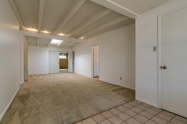 carpeted spare room featuring beam ceiling and a skylight