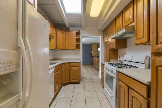 kitchen featuring light tile patterned flooring, white appliances, beam ceiling, and a skylight