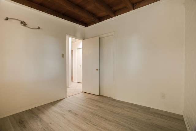 spare room featuring beamed ceiling, wooden ceiling, and light hardwood / wood-style flooring