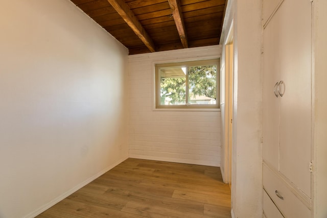 empty room featuring vaulted ceiling with beams, brick wall, hardwood / wood-style floors, and wooden ceiling