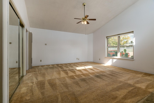 carpeted empty room with high vaulted ceiling and ceiling fan