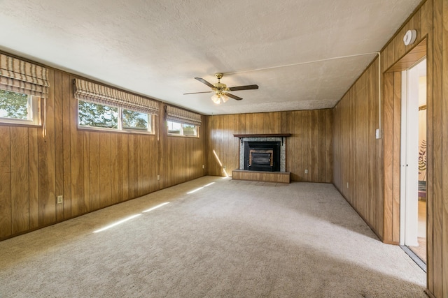 unfurnished living room featuring ceiling fan, wooden walls, and light carpet