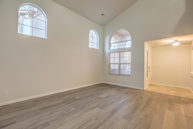 unfurnished room featuring hardwood / wood-style floors and high vaulted ceiling