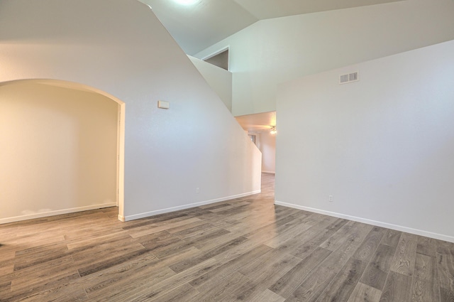 empty room with high vaulted ceiling and hardwood / wood-style floors