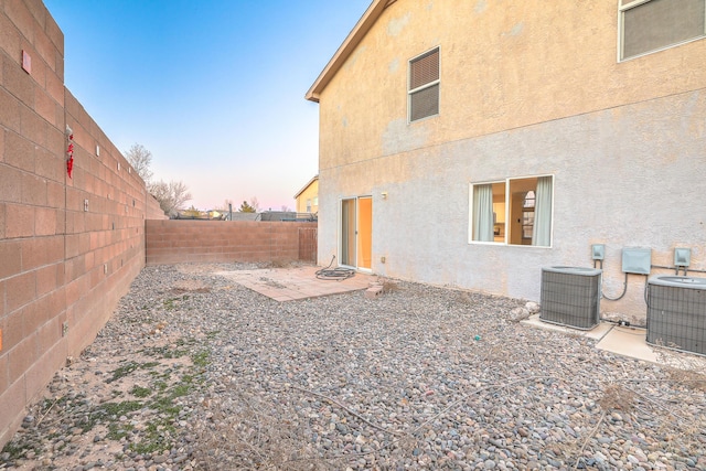 yard at dusk with a patio and central AC