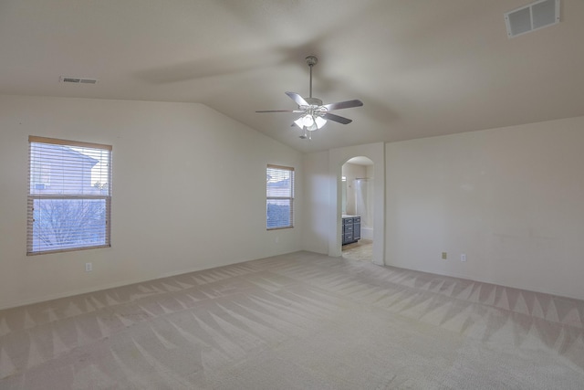 carpeted spare room with ceiling fan and vaulted ceiling