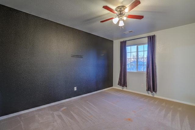 empty room featuring light carpet, a textured ceiling, and ceiling fan