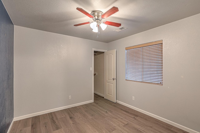 spare room with ceiling fan, light hardwood / wood-style floors, and a textured ceiling